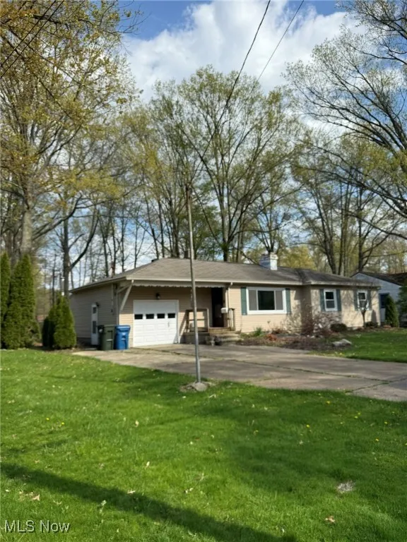 Single story home with a garage, a front lawn, driveway, and a chimney