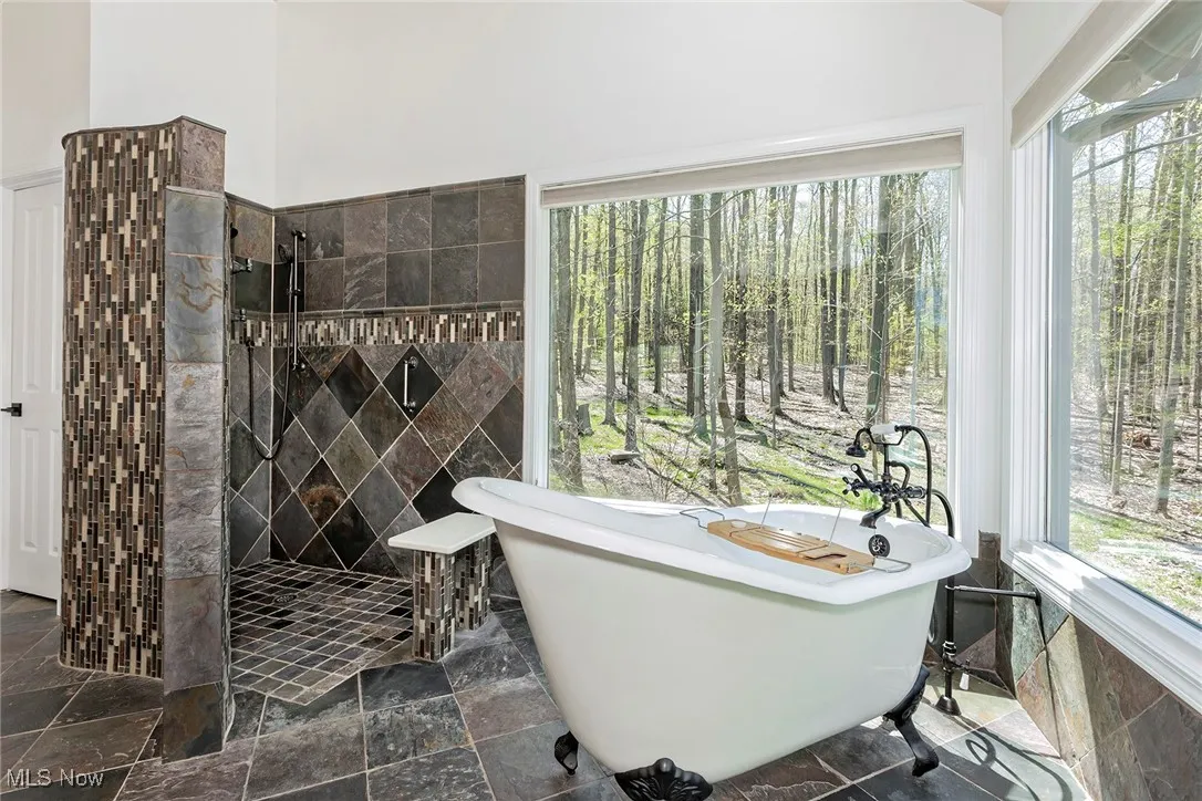 High-style soaking tub set against the privacy of a backyard forest. Master Bath also includes dual vanities, walk-in closet, slate tiled floors.
