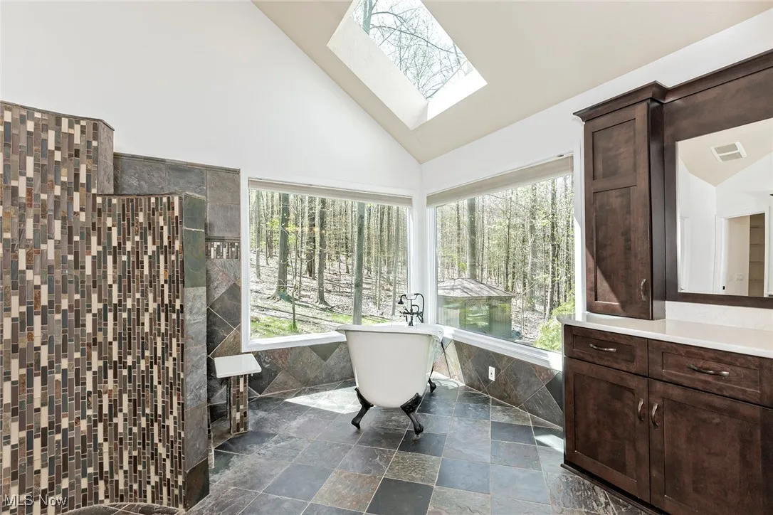 Master Bathroom is flooded with natural light through walls of glass and skylight. A serpentine tiled wall to the left conceals the walkin shower.