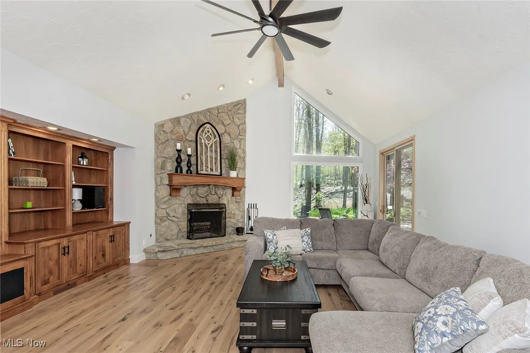 Family Room is highlighted by wall of bookshelves and stone fireplace. To the right is a sliding glass door leading to the patios.