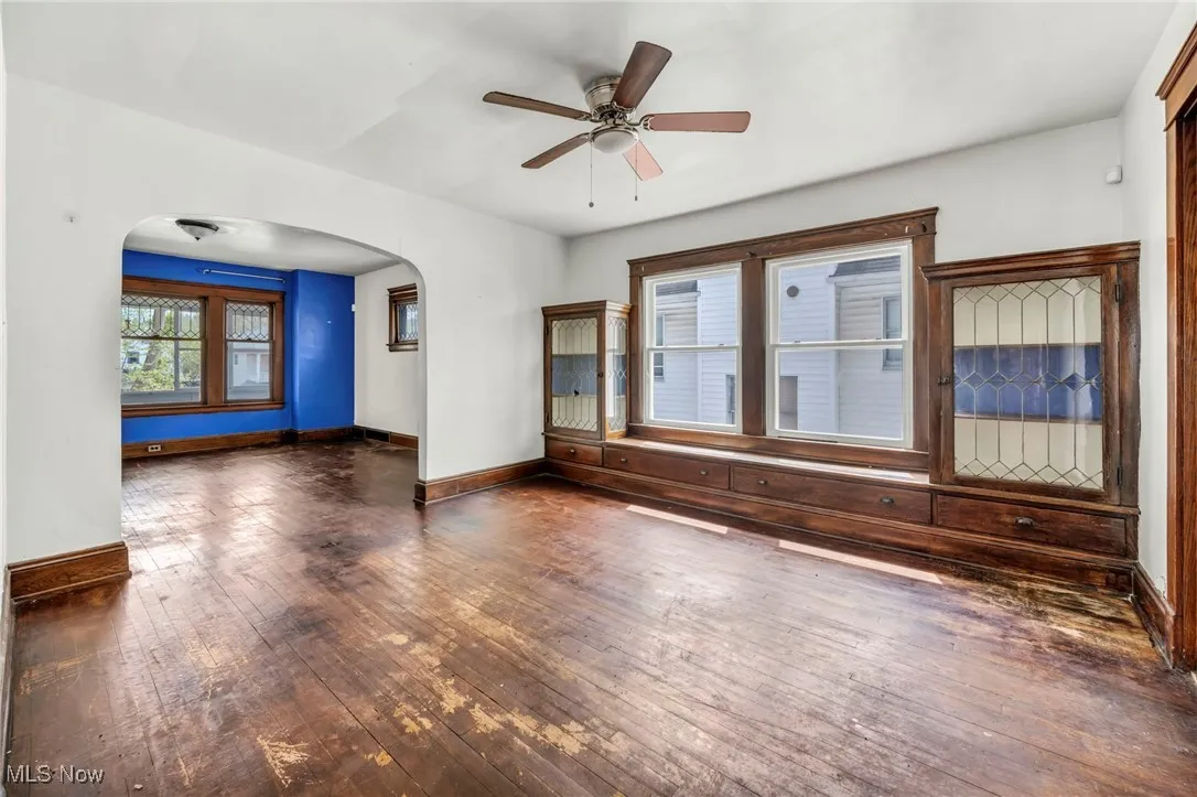 Unfurnished room featuring baseboards, arched walkways, a ceiling fan, and hardwood / wood-style floors