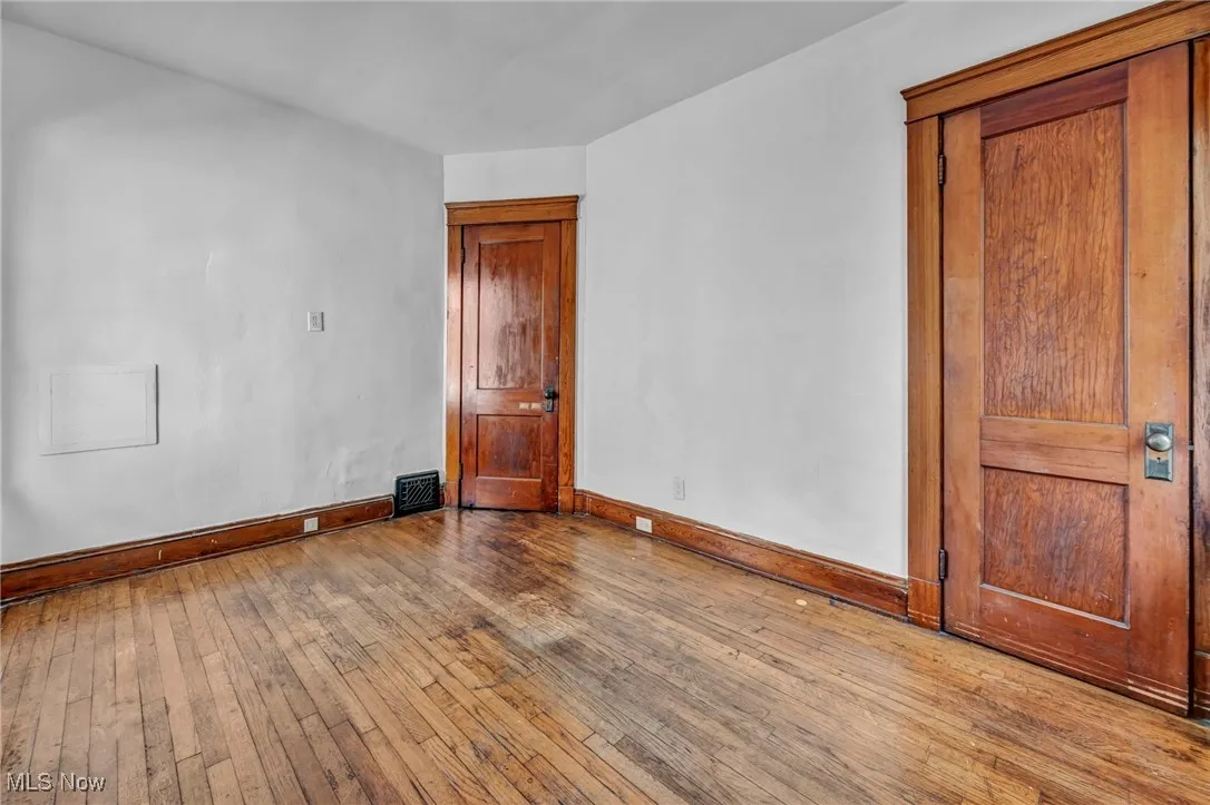 Spare room featuring baseboards, hardwood / wood-style flooring, and visible vents