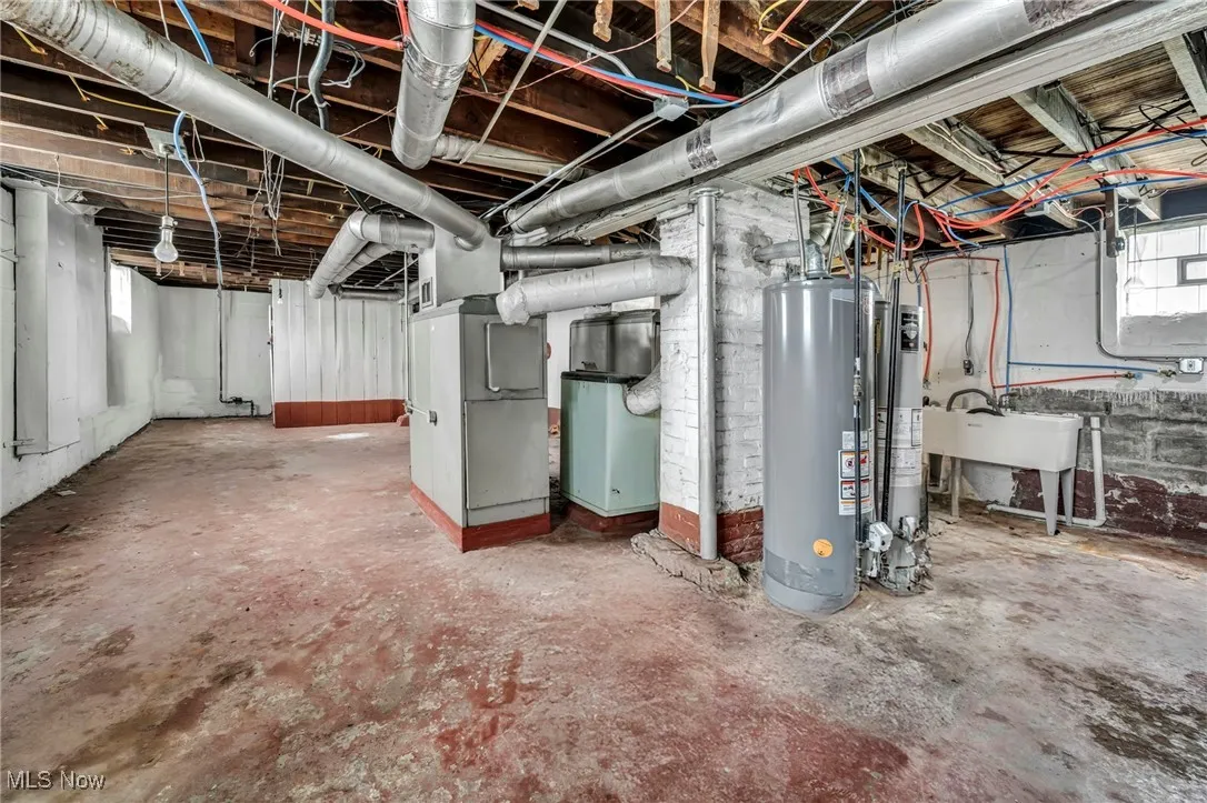 Below grade area featuring heating unit, a sink, and gas water heater