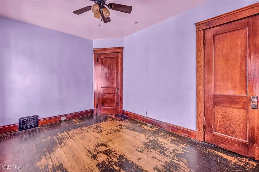 Spare room with ceiling fan, visible vents, baseboards, and hardwood / wood-style floors