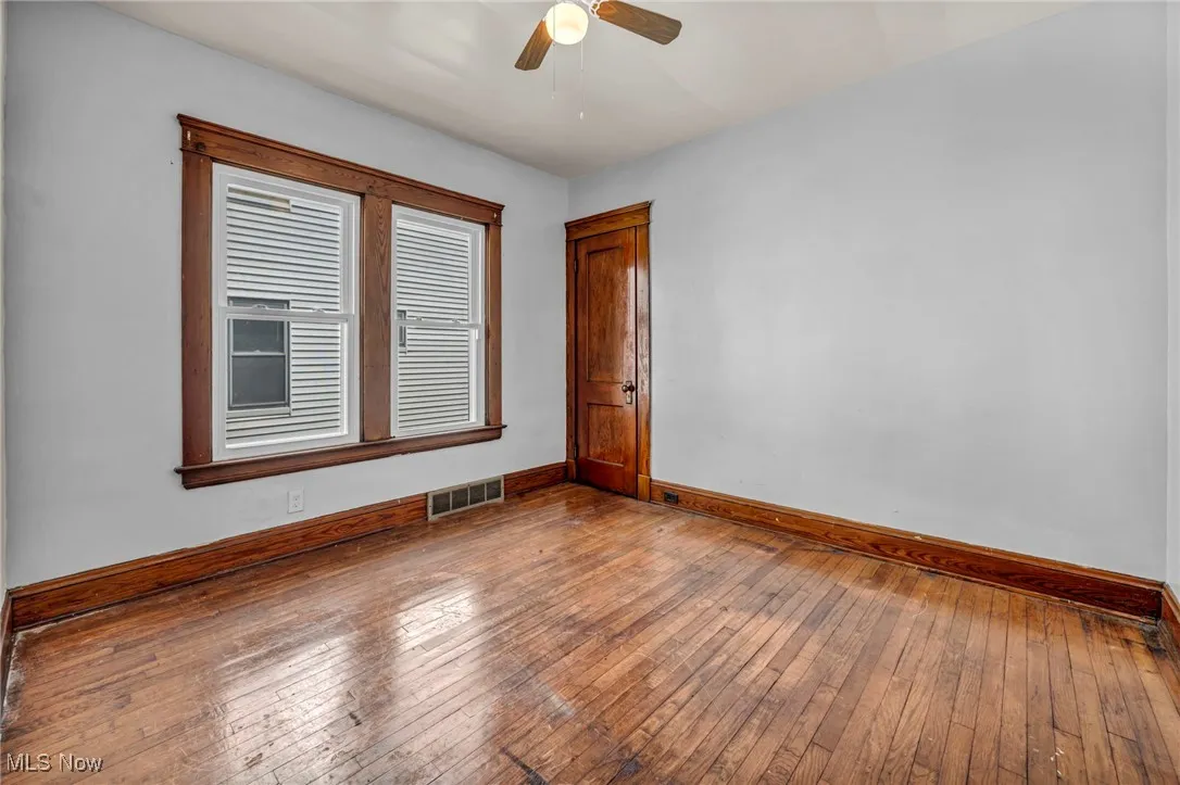 Unfurnished room with baseboards, a ceiling fan, hardwood / wood-style floors, and visible vents