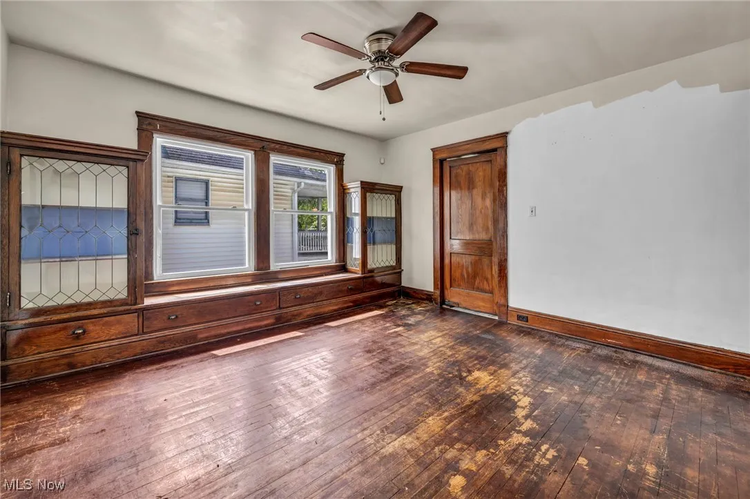 Unfurnished living room featuring wood-type flooring, a ceiling fan, and baseboards