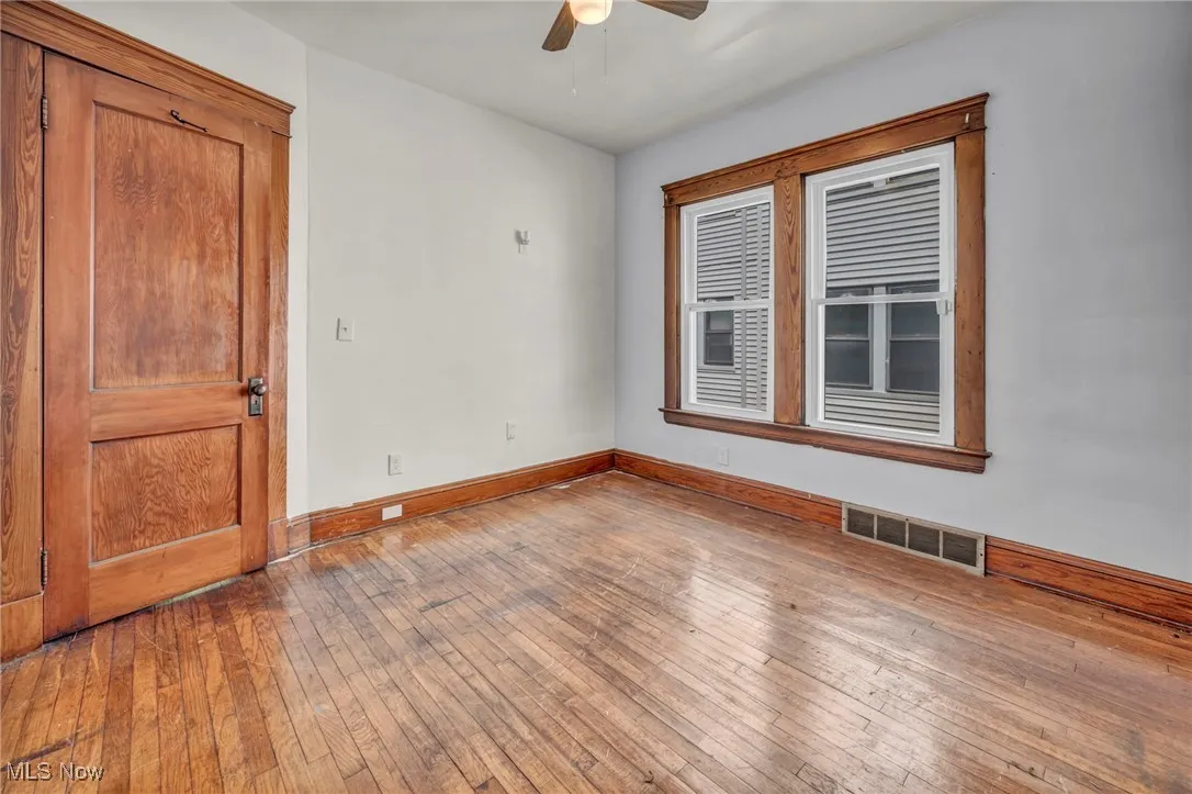 Empty room featuring visible vents, a ceiling fan, baseboards, and wood-type flooring
