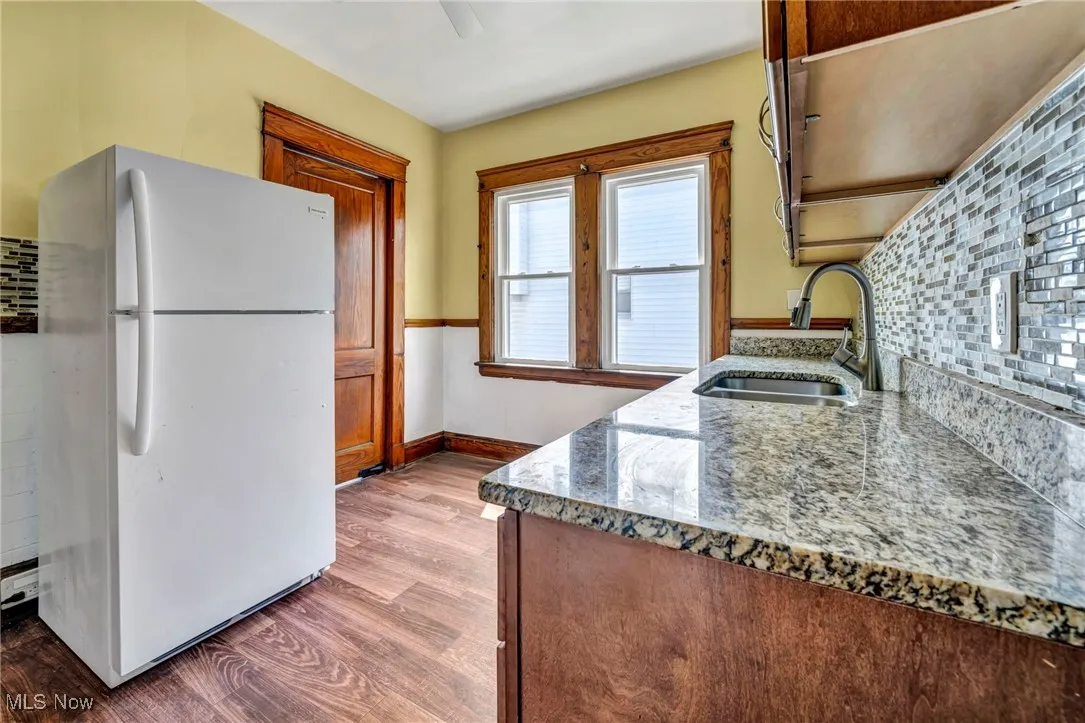 Kitchen featuring freestanding refrigerator, a sink, wood finished floors, and decorative backsplash