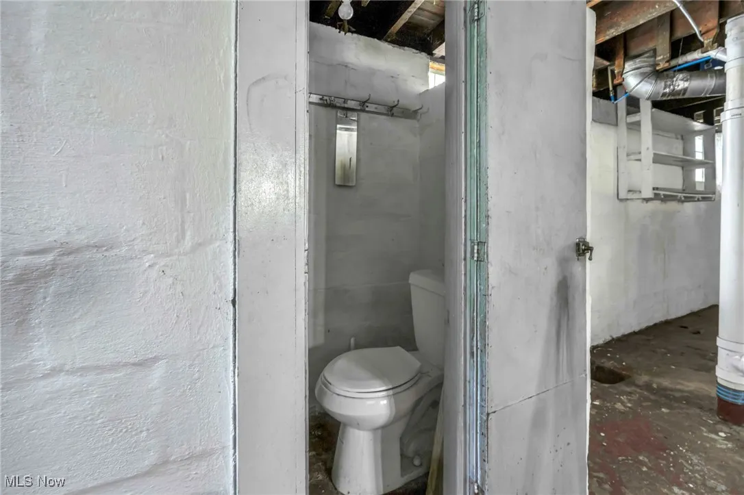 Bathroom featuring toilet and unfinished concrete floors