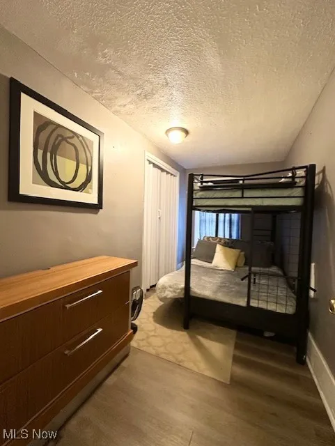 Bedroom with a textured ceiling, lofted ceiling, and light wood finished floors