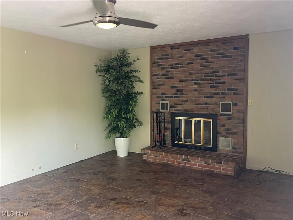 Open Concept Kitchen Family Room Area vents, a fireplace, baseboards, ceiling fan, and a textured ceiling