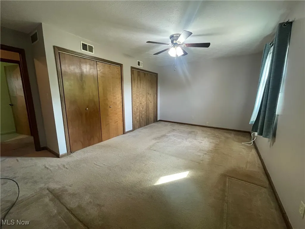 Unfurnished bedroom with multiple closets, baseboards, and visible vents