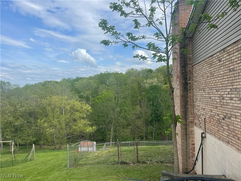 Side View of yard featuring fence, a wooded view, and an outdoor structure