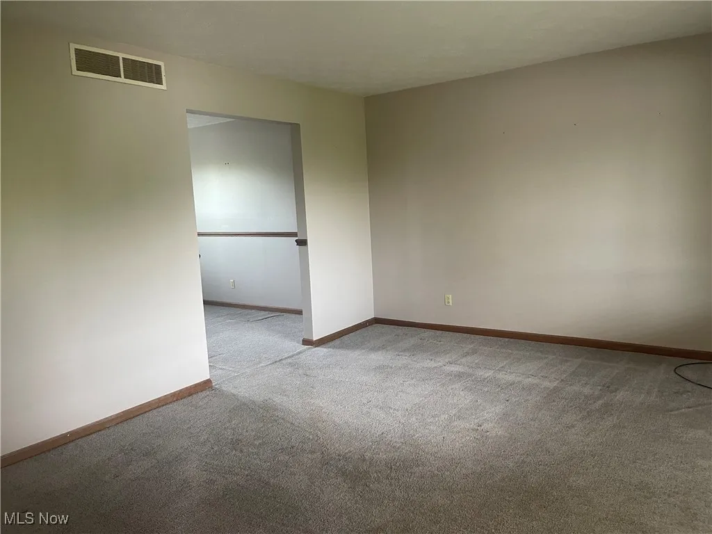 Carpeted spare room featuring baseboards and visible vents