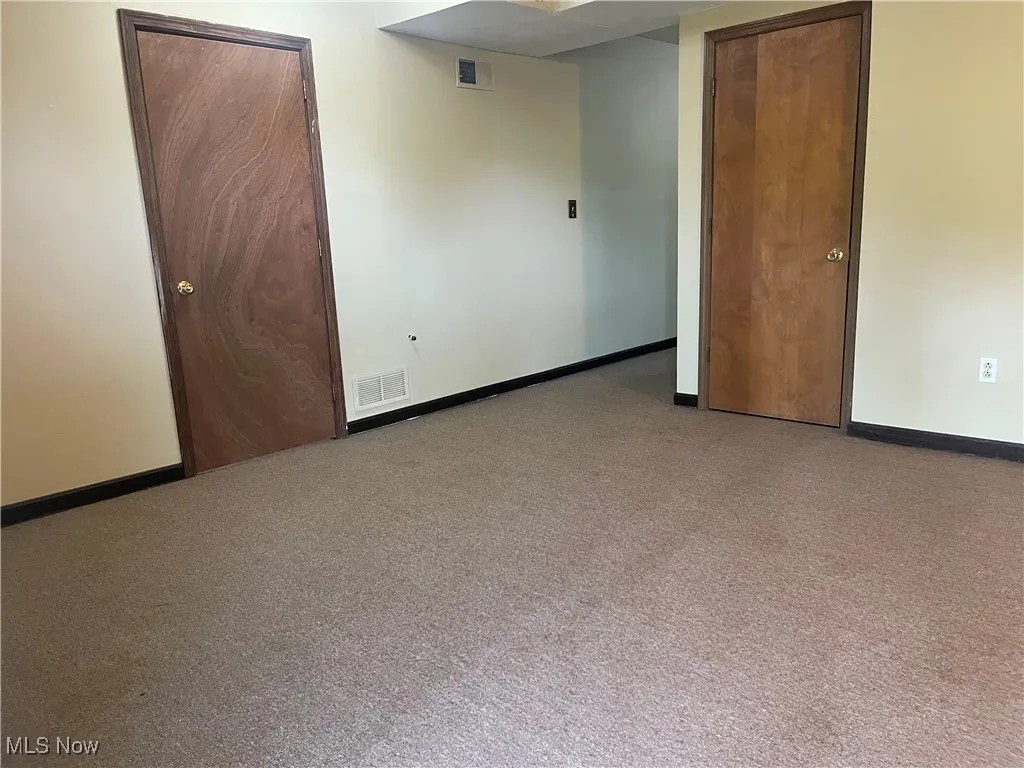 Carpeted empty room featuring baseboards and visible vents