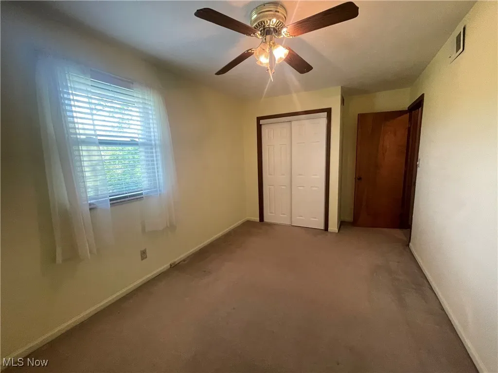 Unfurnished bedroom featuring ceiling fan, carpet floors, baseboards, visible vents, and a closet