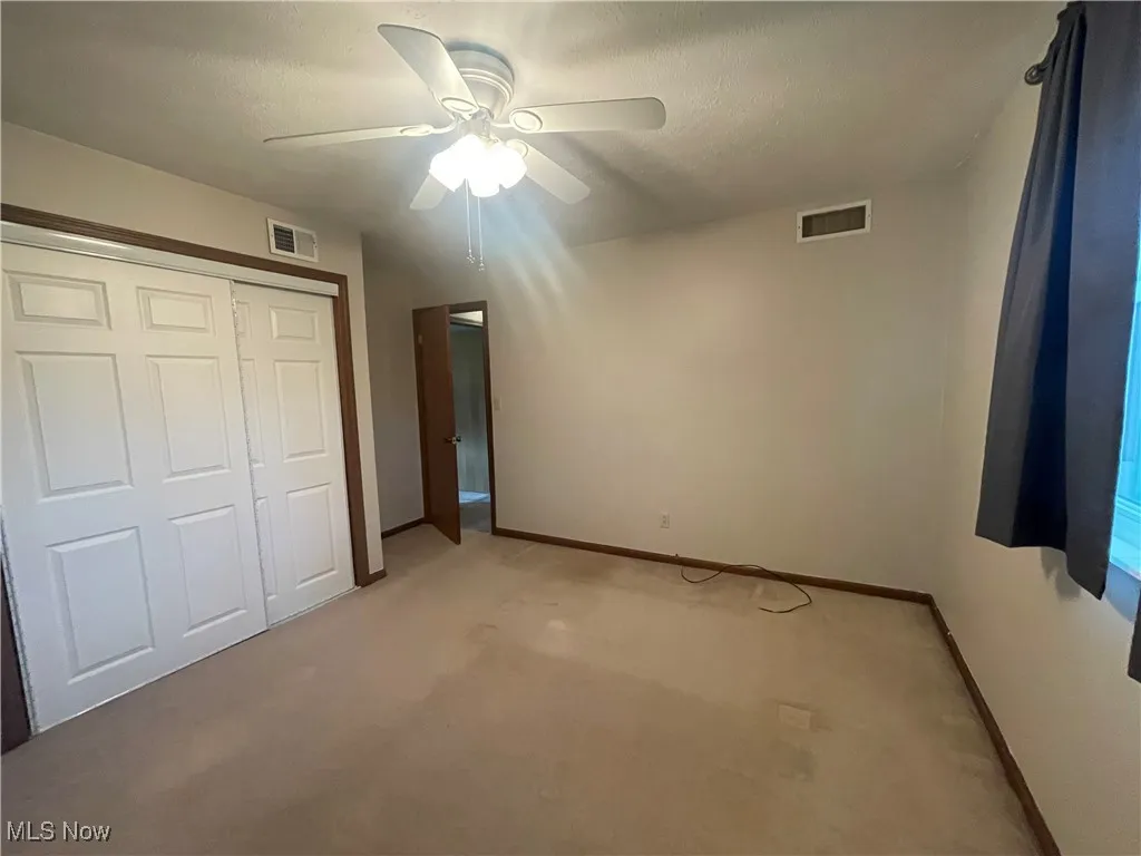 Unfurnished bedroom featuring baseboards, light carpet, a closet, and visible vents