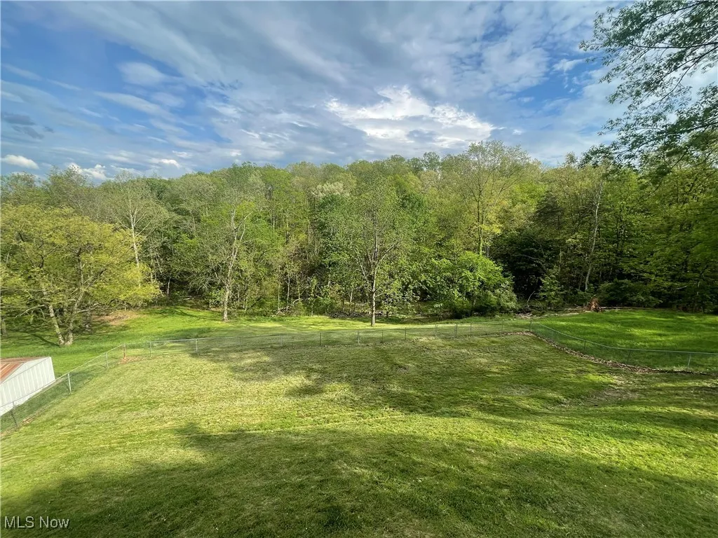 View of yard with fence and a wooded view