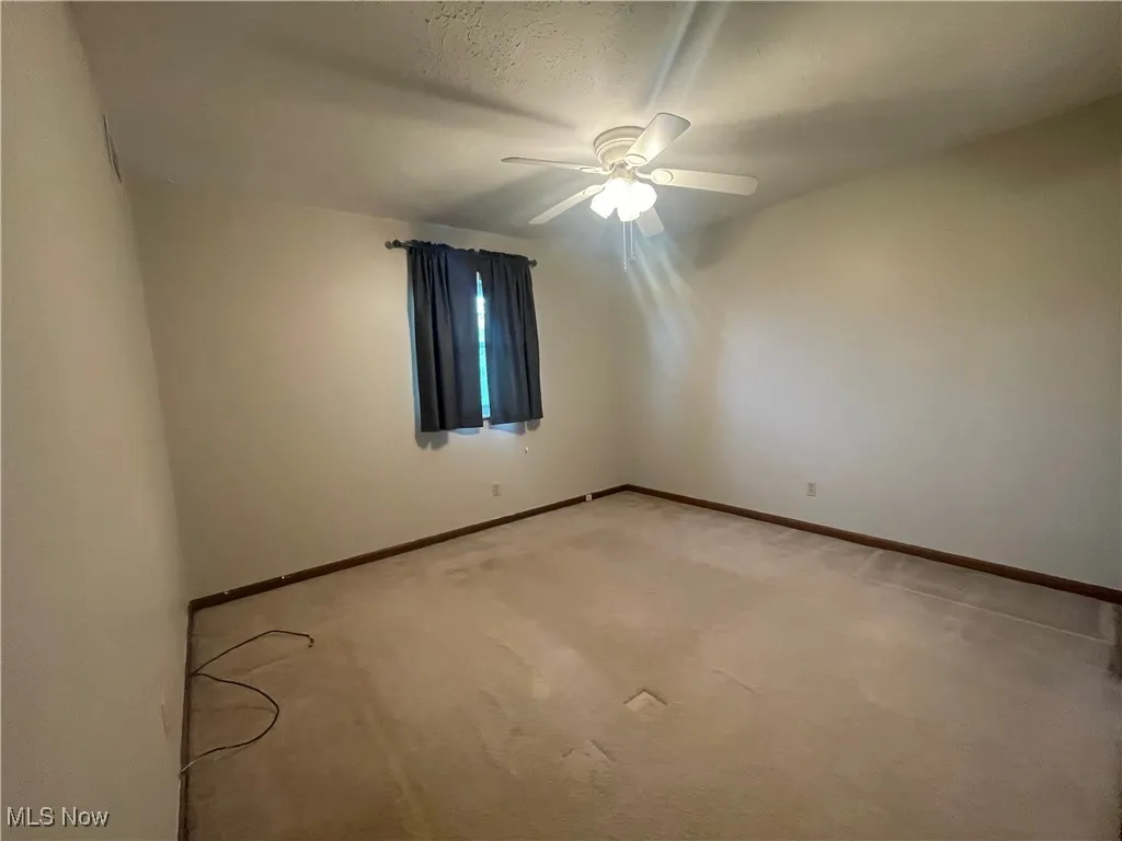 Empty room with baseboards, ceiling fan, and light carpet