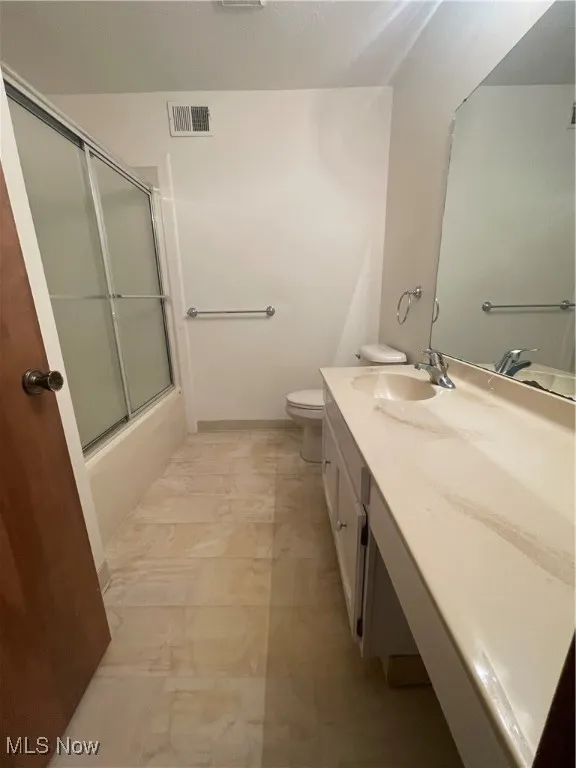 Bathroom with visible vents, vanity, toilet, shower / bath combination with glass door, and marble finish floor