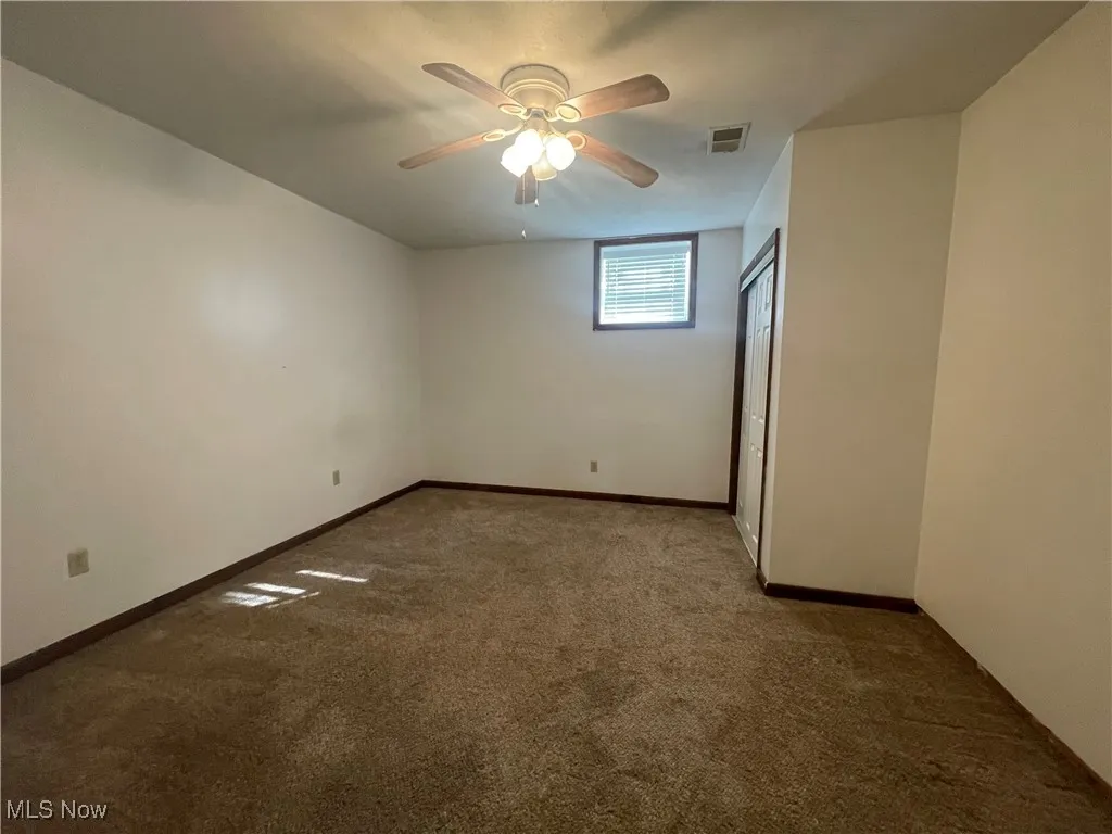 Lower Level Carpeted spare room with baseboards, ceiling fan, and visible vents