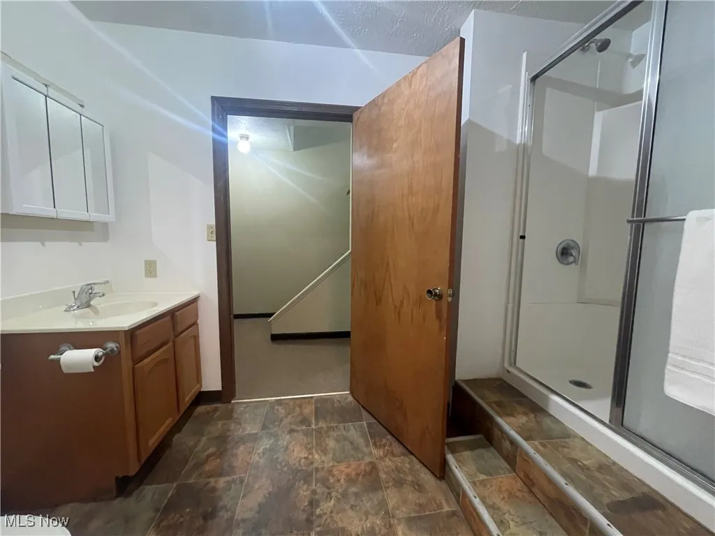Lowe Level Full bathroom off Bedroom  with vanity, stone finish floor, and a stall shower