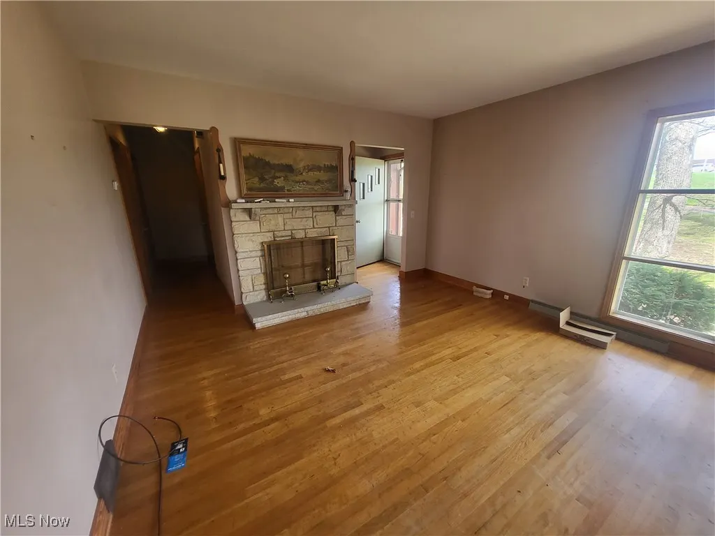 Unfurnished living room featuring light wood-type flooring, baseboards, and a fireplace