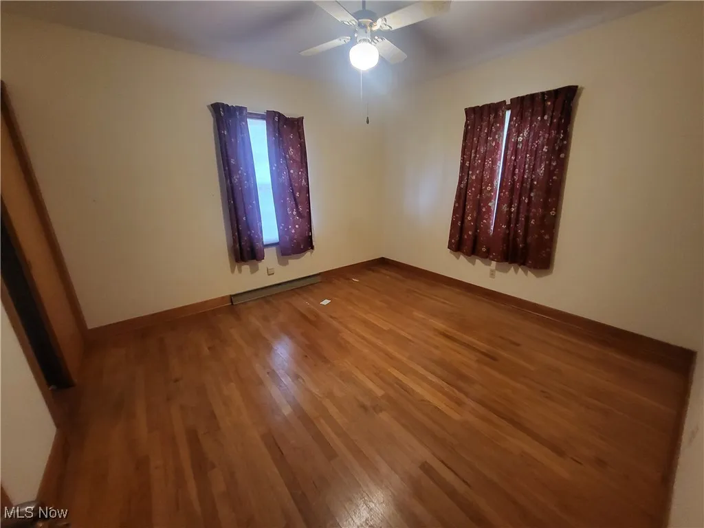 Unfurnished room with baseboards, ceiling fan, and wood finished floors
