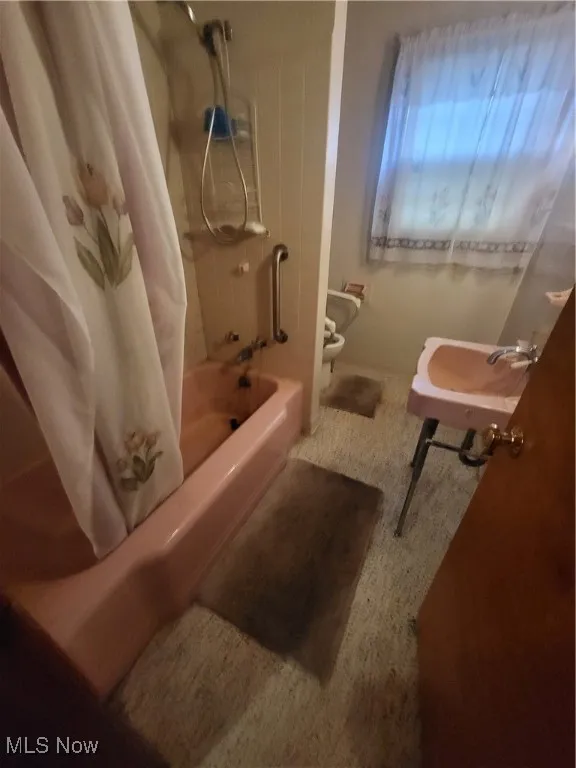 Bathroom with a sink, toilet, and shower / bathtub combination with curtain