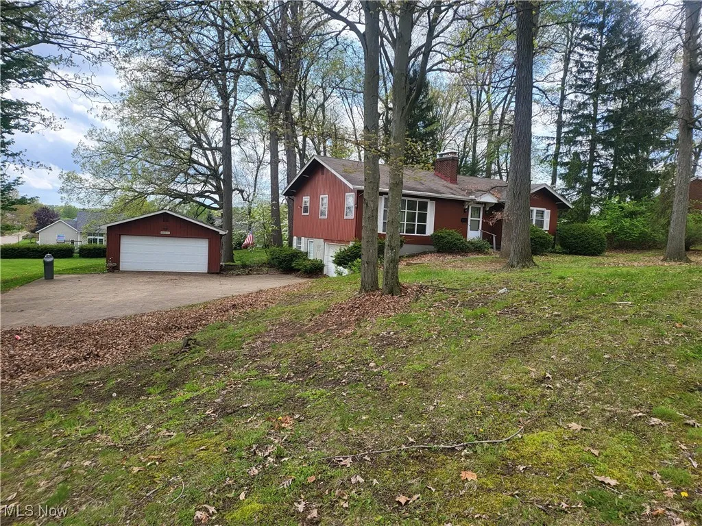 View of side of home featuring a detached garage, an outbuilding, and a chimney