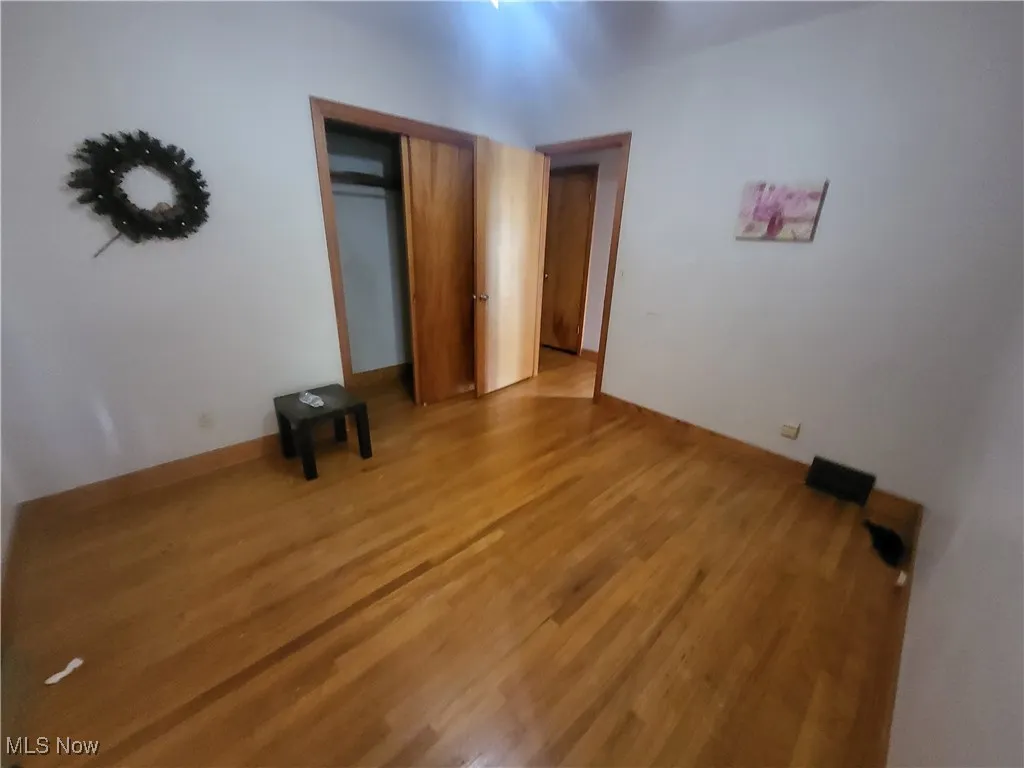 Unfurnished bedroom with a closet, baseboards, and light wood-style floors
