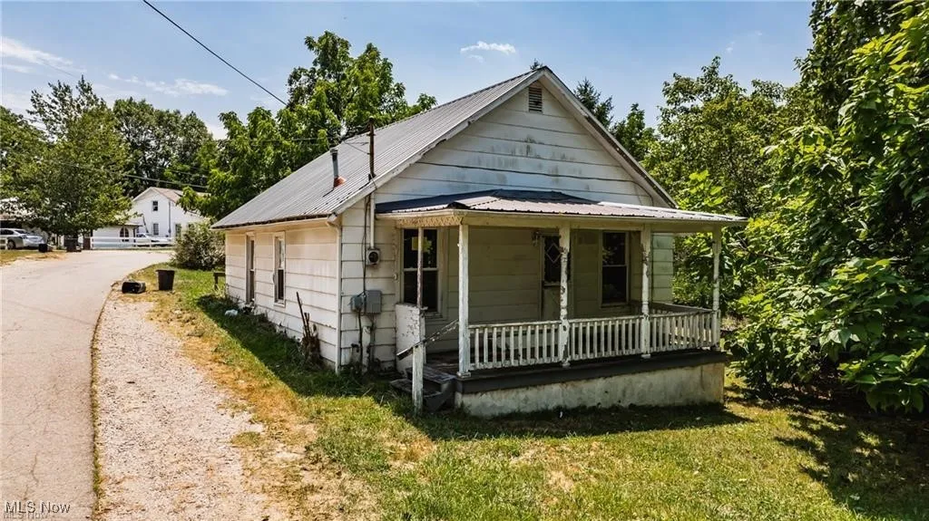 Bungalow-style house featuring a porch, metal roof, and a front lawn