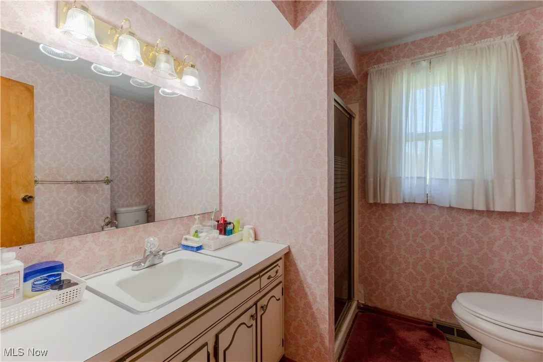 Bathroom featuring vanity, visible vents, toilet, and a shower stall