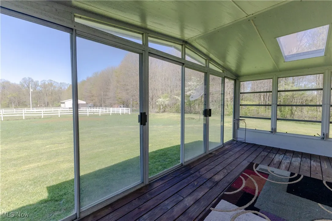 Unfurnished sunroom featuring a skylight, a forest view, and a healthy amount of sunlight