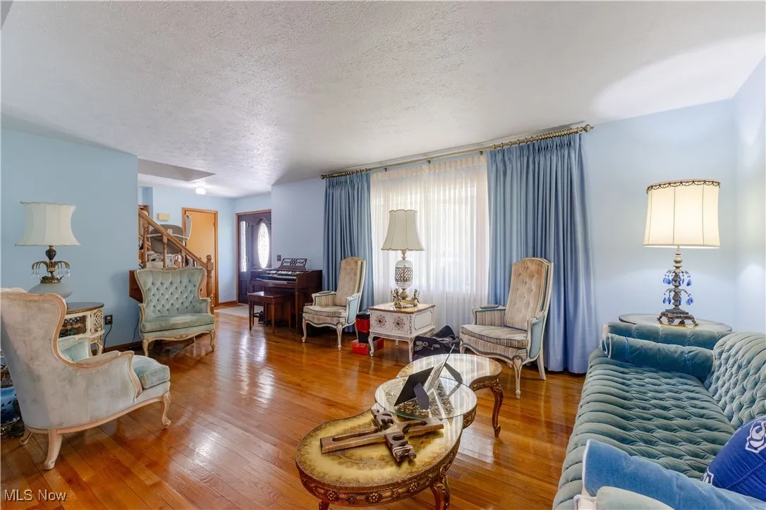Living room with stairs, a textured ceiling, and wood finished floors