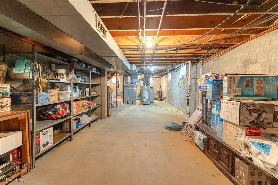Unfinished basement featuring water heater, heating unit, and visible vents