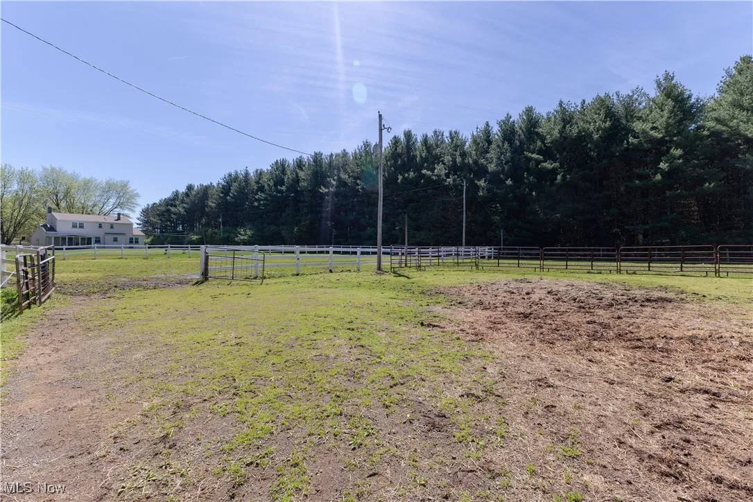 View of yard featuring an enclosed area, fence, a rural view, and a forest view