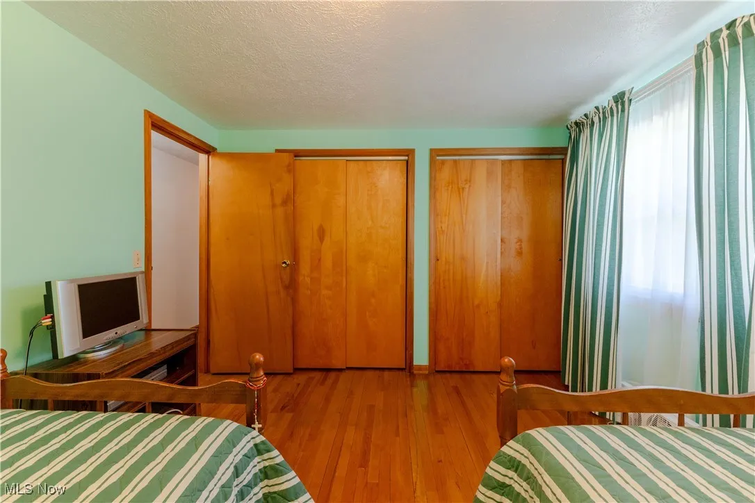 Bedroom featuring a textured ceiling, two closets, and wood finished floors