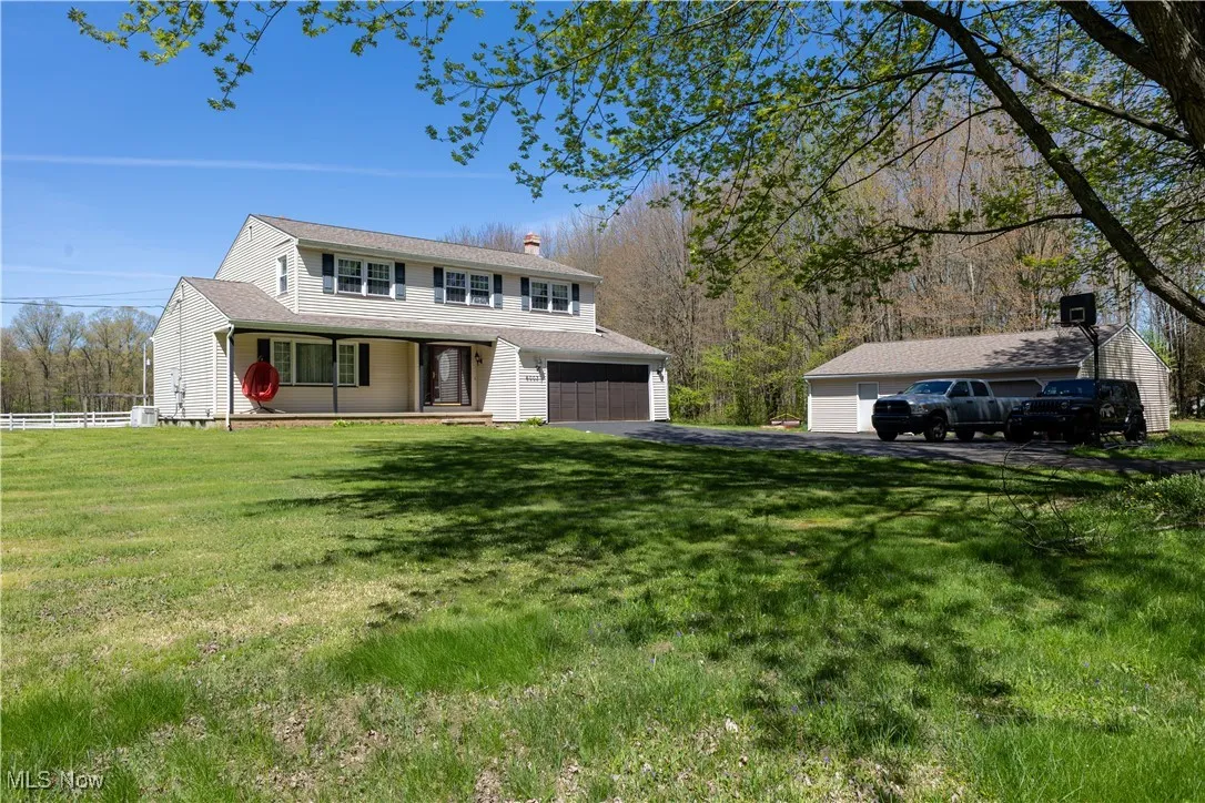 View of front of property with a front lawn, aphalt driveway, a garage, a chimney, and covered porch