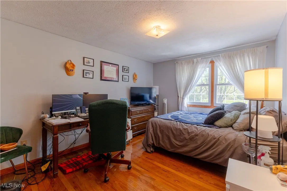 Bedroom with a textured ceiling and wood finished floors