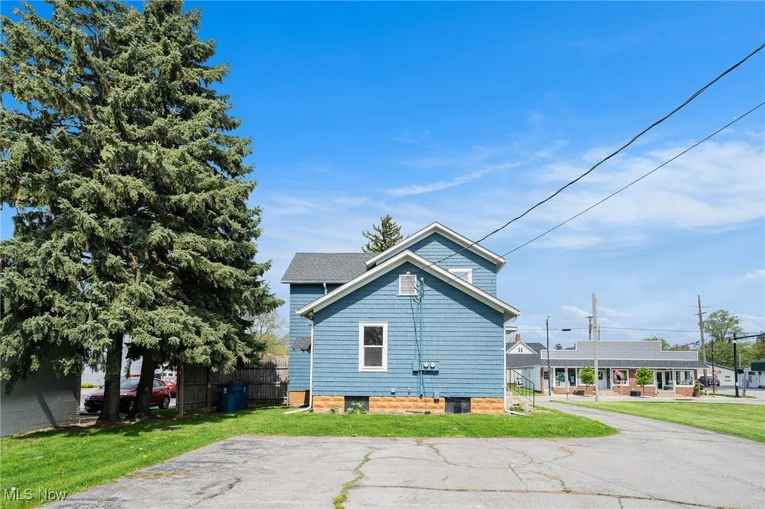 View of side of property with a lawn and fence