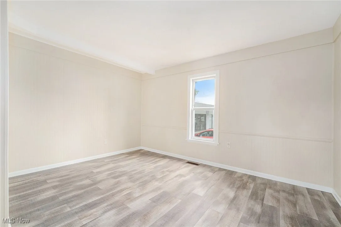Empty room featuring baseboards, visible vents, and wood finished floors