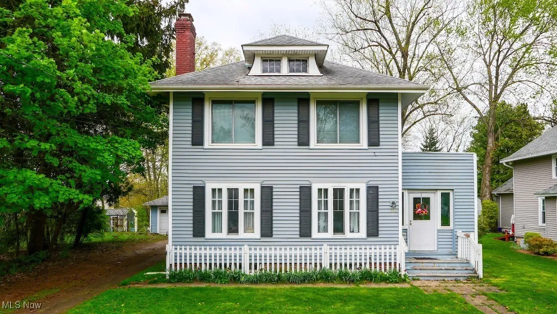Traditional style home featuring a chimney and a front lawn
