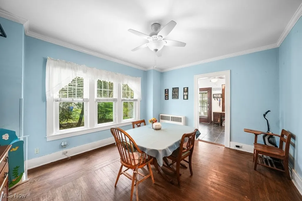 Dining room featuring dark wood-style flooring, a ceiling fan, plenty of natural light, and radiator heating unit