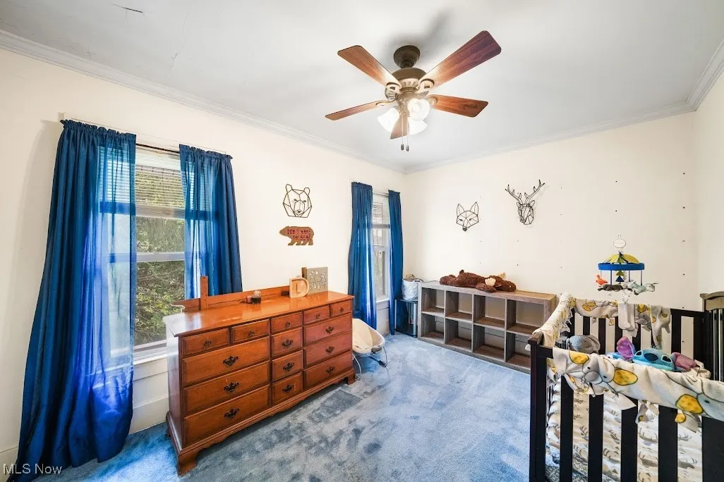 Bedroom with carpet floors, ornamental molding, and a ceiling fan