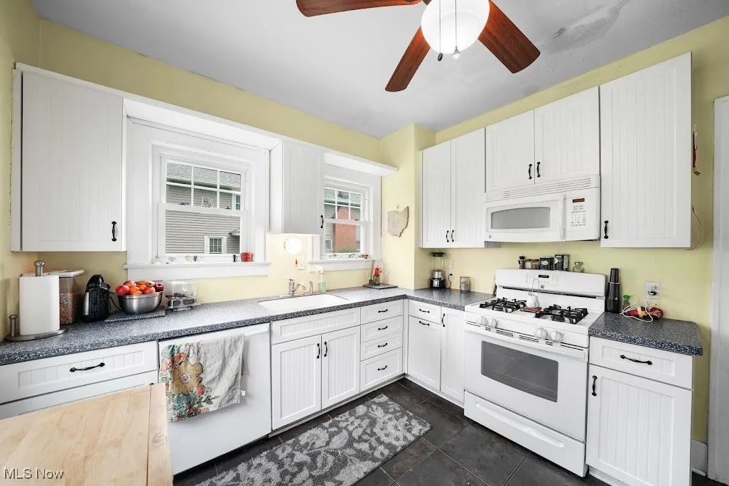 Kitchen featuring a sink, a ceiling fan, white cabinets, and white appliances