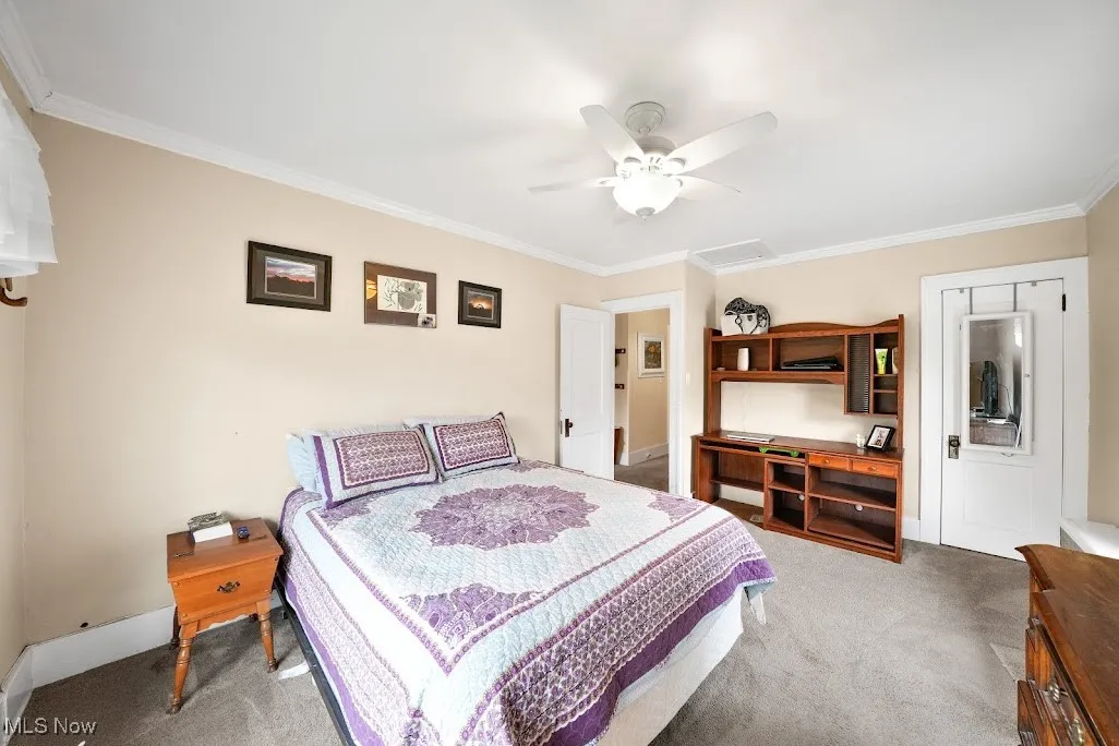 Carpeted bedroom with crown molding, ceiling fan, and baseboards