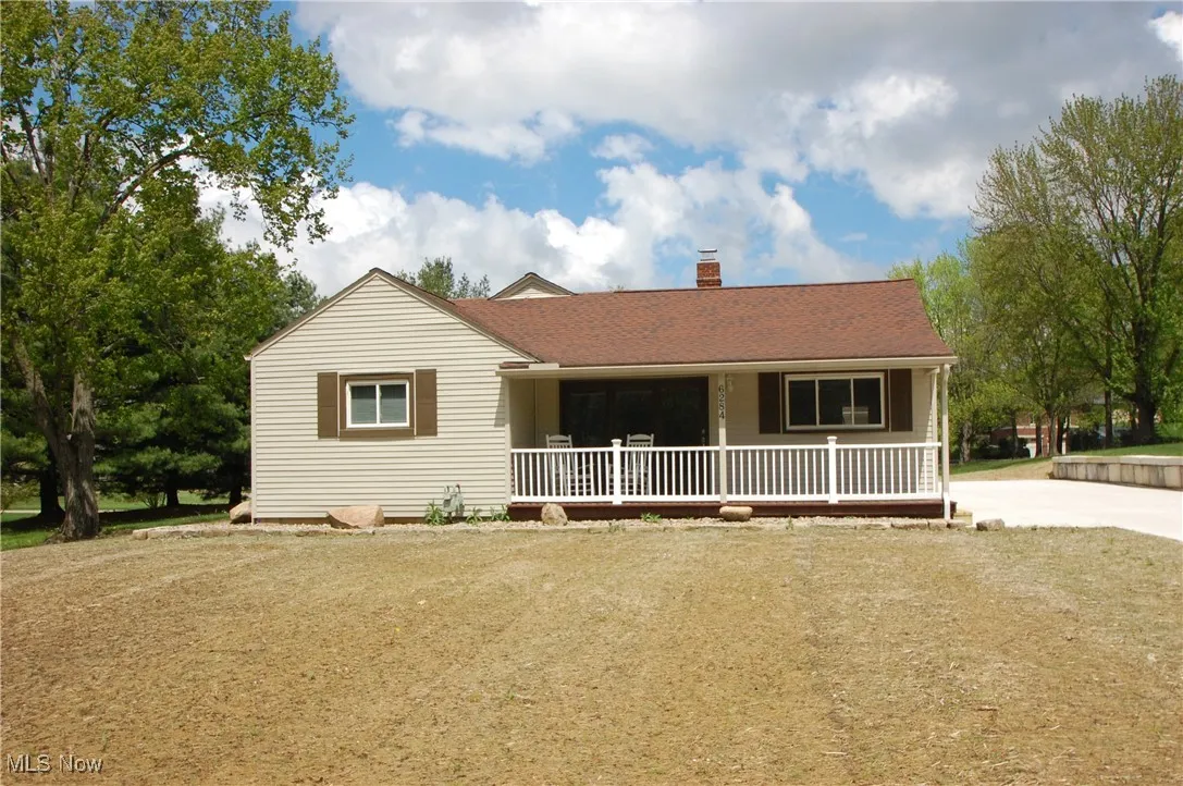 View of front of home with a porch, roof with shingles, and a chimney