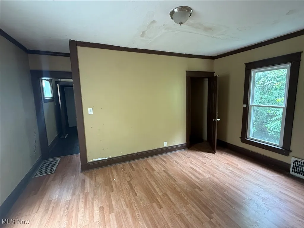Unfurnished room featuring light wood-style flooring and crown molding