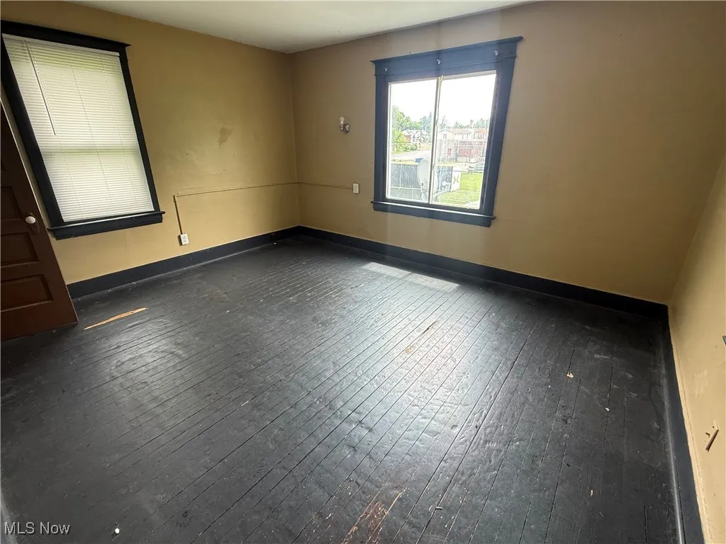 Unfurnished room with dark wood finished floors and baseboards